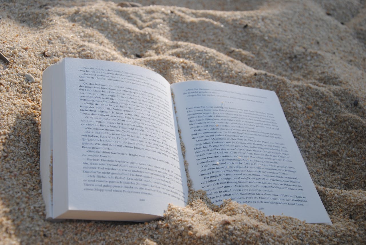 A book open on a sandy beach, representing relaxation and leisure reading.