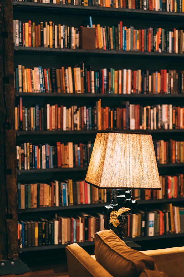 Warmly lit library with bookshelves and a reading lamp creating a cozy ambiance.