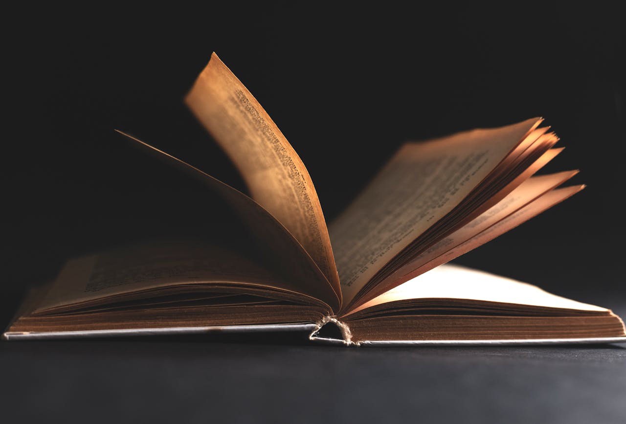 Captivating shot of an antique book with turning pages, highlighted against a black background.