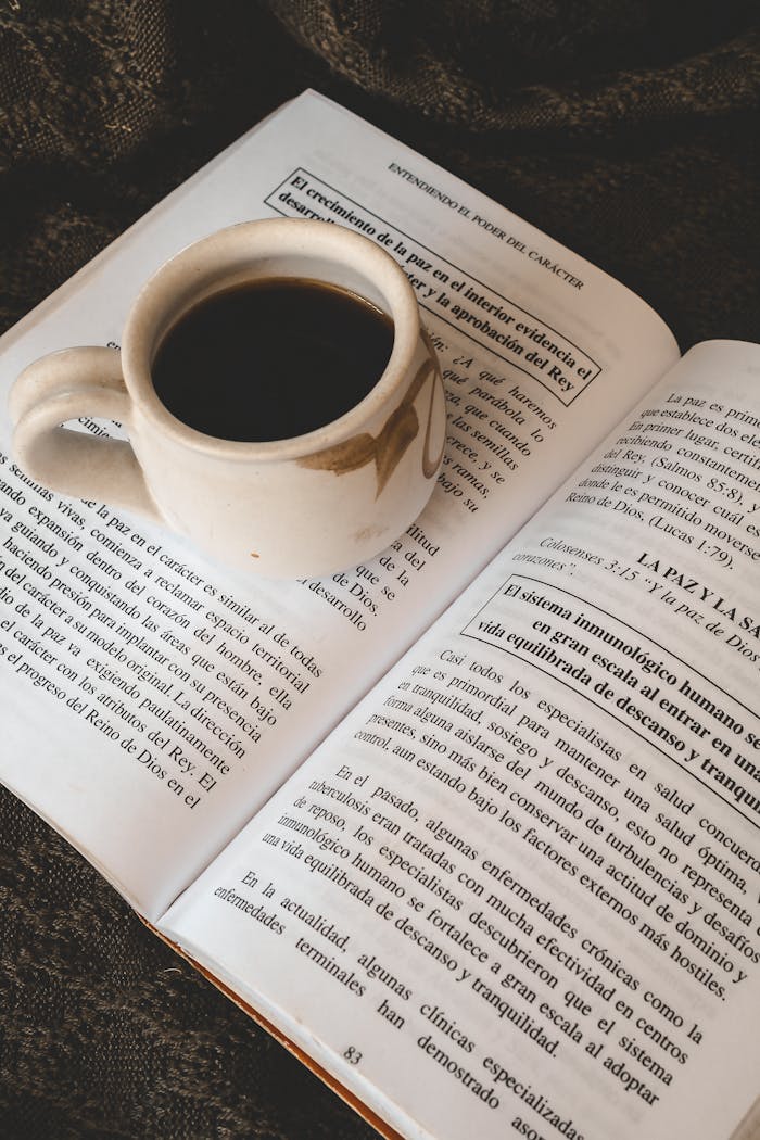 A cup of coffee resting on an open book, perfect for a cozy reading session.