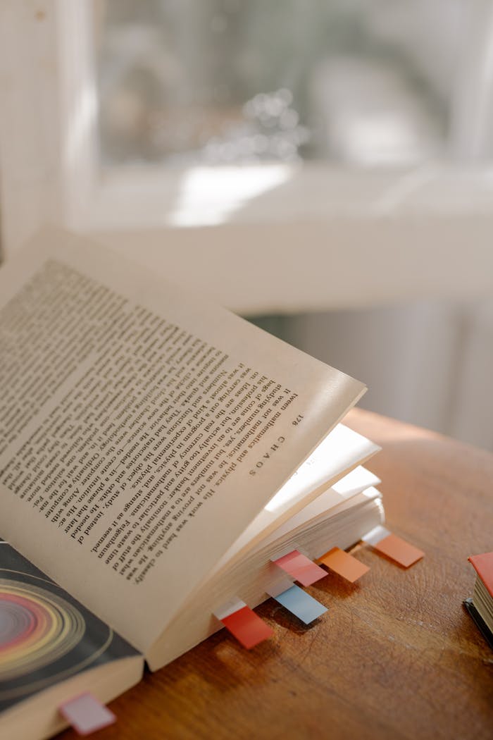 Open book with vibrant bookmarks, basking in warm natural light.