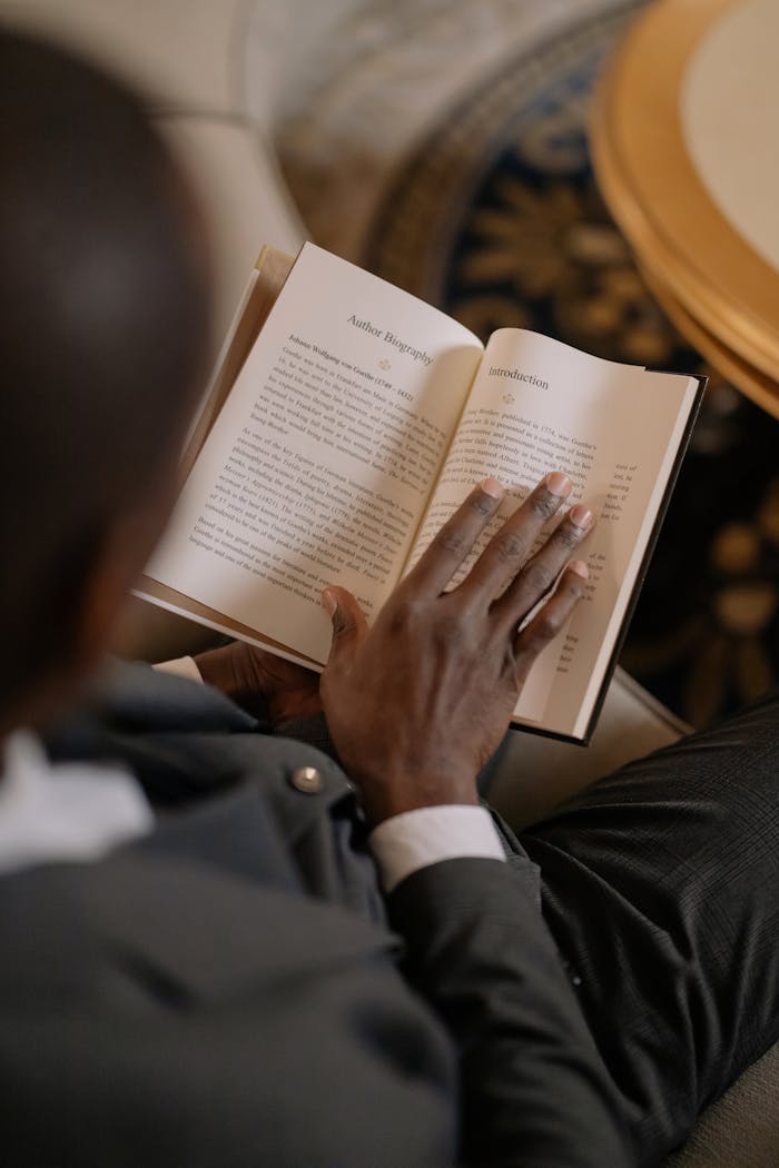A man is reading a book indoors, providing a perspective on knowledge and learning.