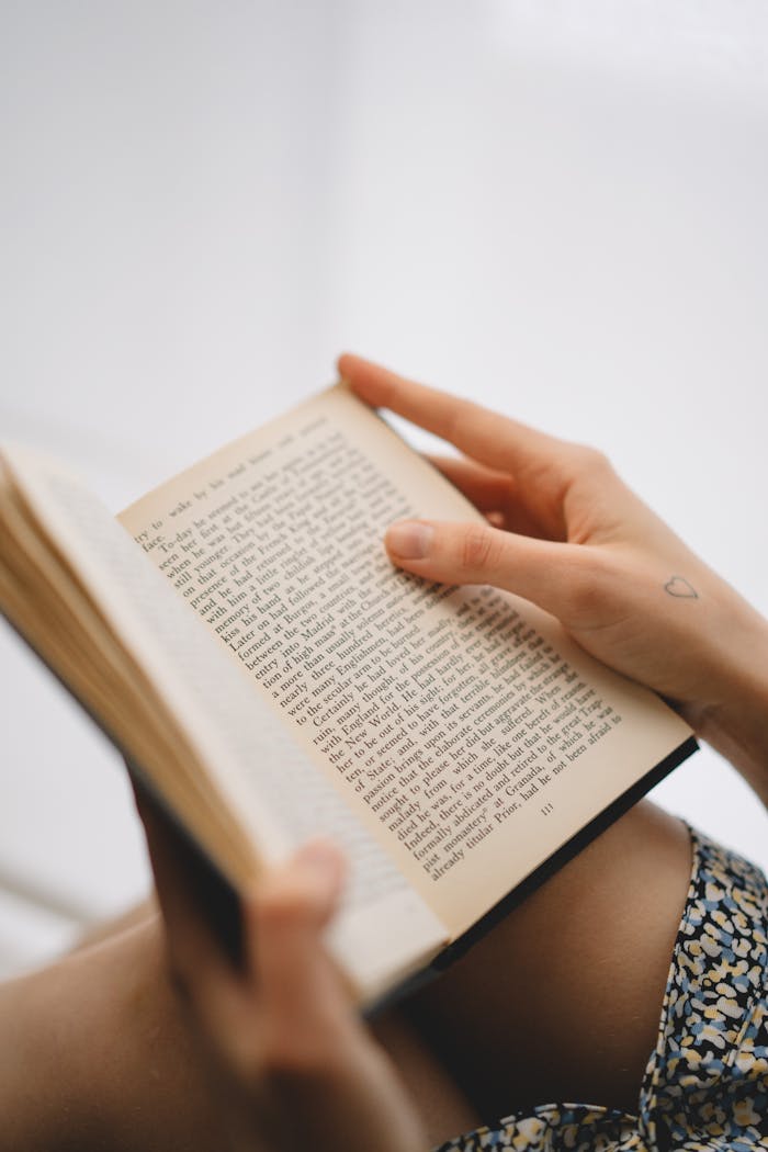 Hands holding an open book with visible text, focusing on reading and literature.